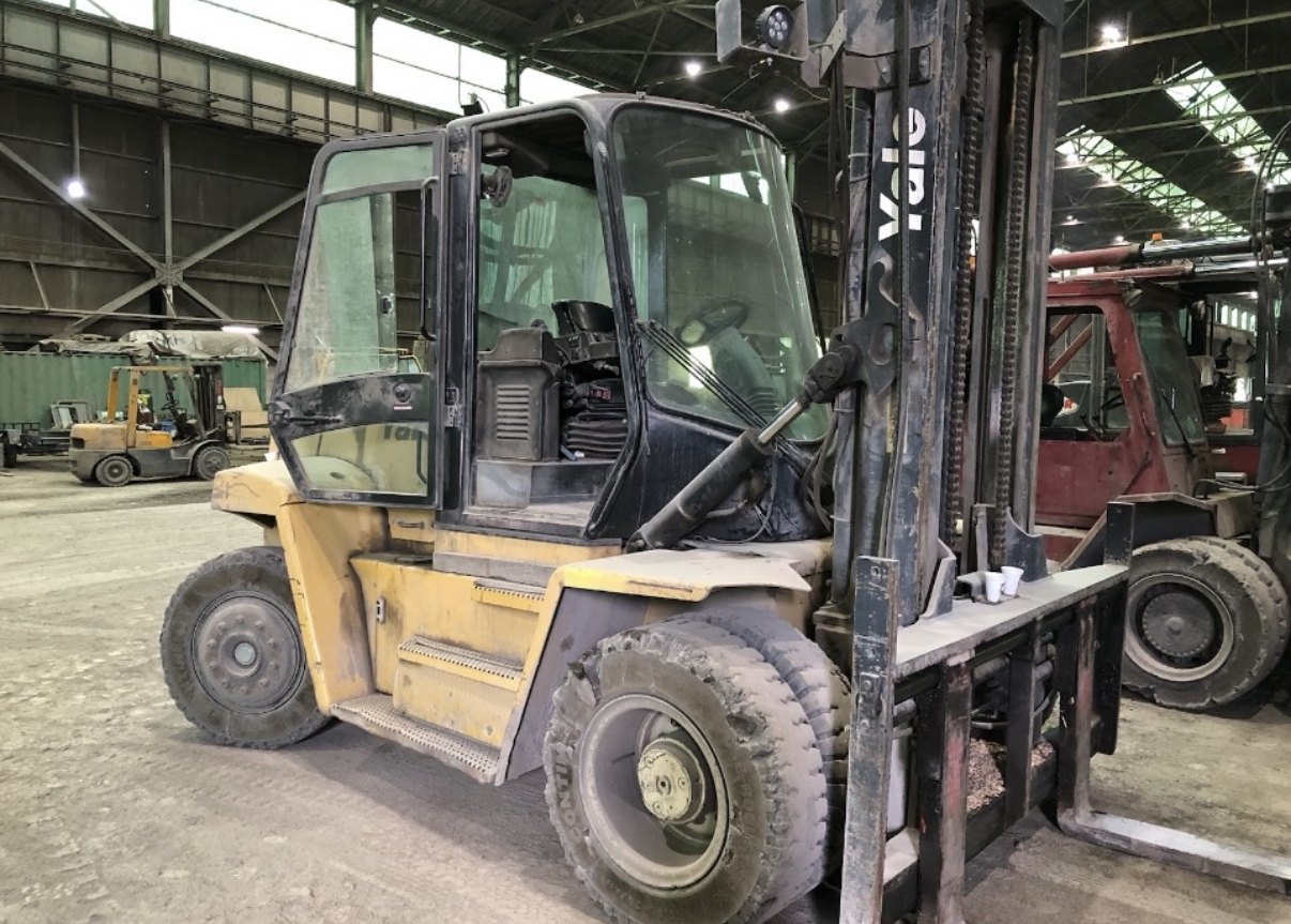 Large enclosed-cab Yale diesel forklift inside an industrial plant alongside additional lift trucks