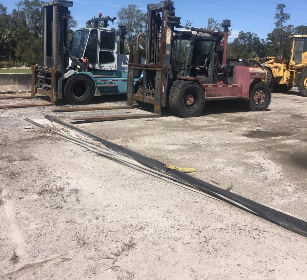 Two large used pneumatic-tire forklifts parked side by side on a Florida equipment lot awaiting export